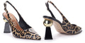 A pair of pointed-toe slingback pumps with a black and beige leopard print pattern, featuring a black block heel with a metallic gold spherical accent on the side.